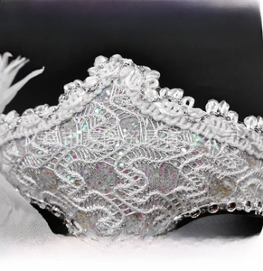 Close-up of white lace masquerade mask showing intricate silver edging and colorful glitter