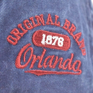 Close-up of vintage Orlando embroidery and 1876 brand logo on washed denim cap