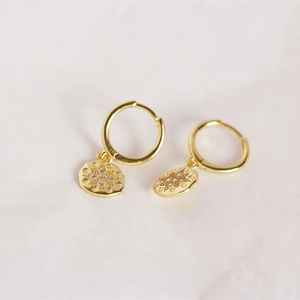 Macro detail of gold S925 silver hoop earrings with diamond octagonal star pendants