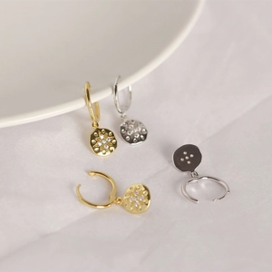 Macro detail of S925 sterling silver hoop earrings with starburst rhinestone pendants