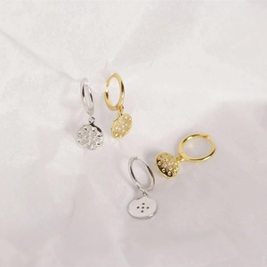 Detailed view of gold and silver starburst earrings with relief pattern and leverback hoops