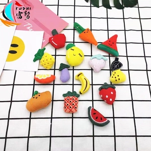 Flat lay of colorful plush fruit and vegetable DIY accessories on checkered background