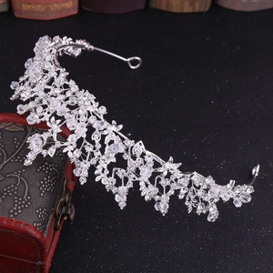 Close-up of silver bridal crown with intricate crystal floral vine design on black surface