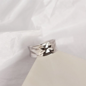 Macro shot of minimalist silver irregular concave ring with liquid metal texture finish