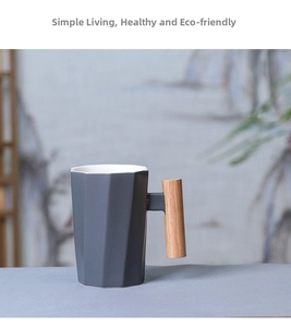 Detail of geometric ceramic mug with vertical wooden handle and matte gray finish