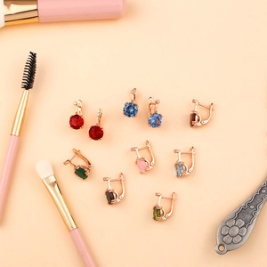 Mise à plat de boucles d'oreilles en or rose avec zircons colorés sur fond beige élégant
