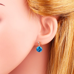Détail d'une boucle d'oreille en or rose avec pierre bleue et zircon brillant pour femme
