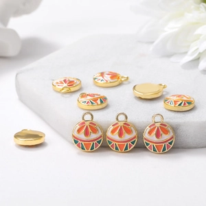 Detailed view of metal peacock fan charms with colorful enamel floral patterns