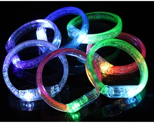 Close-up of LED glowing bracelets with colorful bubbles texture on dark background