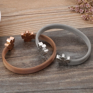 Mesh bracelet in rose gold and silver finish with angel charm on a wooden background