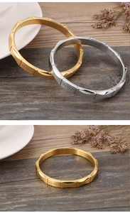 Detail van goud- en zilverkleurige bamboe armbanden met LOVE gravure op houtoppervlak