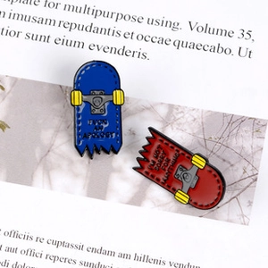 Close-up of dual-color broken skateboard enamel pins on a stylish book background