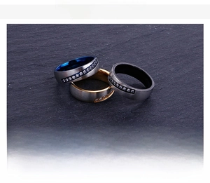 Detailed view of three stainless steel rings in gold, blue, and black with inset crystals