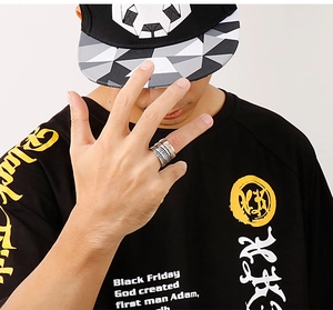 Detailed view of multilayer stainless steel ring in black, silver, and gold on model hand