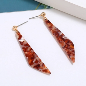 Detail of brown tortoiseshell acetate blade earrings with golden metal accents