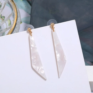 Detail view of long white shell texture resin earrings on white display card