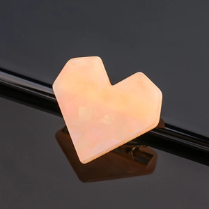Macro detail of heart-shaped orange acetate hair clip with marble texture and metal base