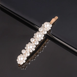 Detailed close-up of premium white pearls on a gold hair clip over a black reflective surface