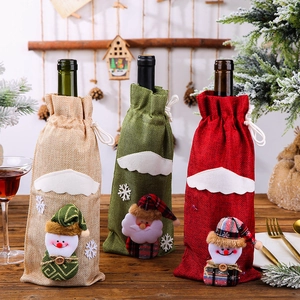 Three Christmas burlap wine bottle bags featuring Santa and snowman motifs for table decor