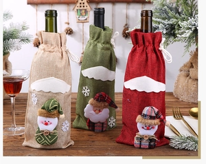 Close-up of three festive linen Christmas wine bottle covers with Santa and snowman 3D decor