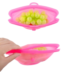 Detailed view of pink silicone food storage bag containing grapes and folded for portability
