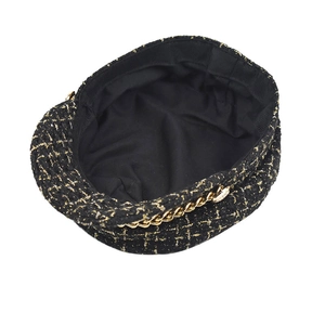 Detail of black tweed baker boy hat with gold metallic threads and chain decoration