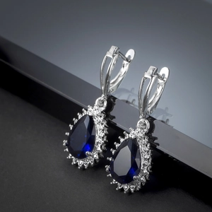 Macro shot of silver leverback earrings with blue pear-shaped stone and white zircon halos