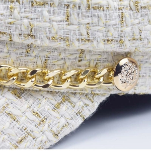 Detail of tweed wool newsboy hat featuring gold chain and embossed metal button