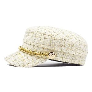 Detail of tweed newsboy cap with gold thread weaving and chunky metallic chain