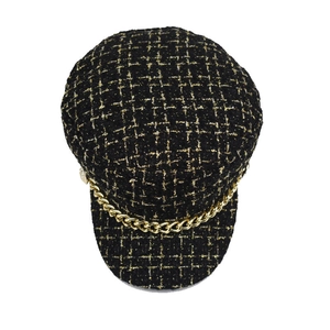 Fashionable tweed newsboy cap in black and gold with a metal chain decoration