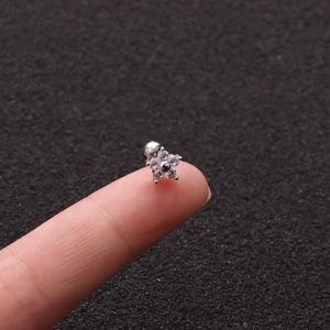 Macro view of a small silver star-shaped gecko screw stud earring on a fingertip