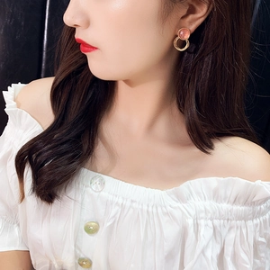 Close-up of model wearing gold layered round earrings with pink resin inlay detail