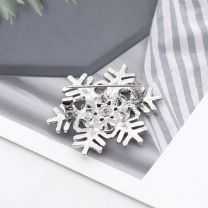 Silver snowflake brooch rear view with pin fastener on dark grey card and striped fabric