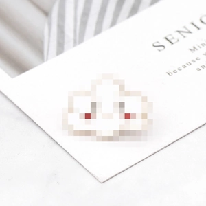 Close-up of a cute white enamel cloud brooch with a smiling face and blushing cheeks