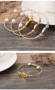 Detail of 18k gold plated steel wire bracelet with pearls and coin charm pendants