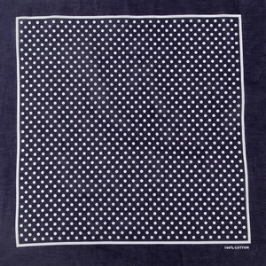 Close-up of navy blue cotton bandana featuring white polka dots and 100% cotton mark