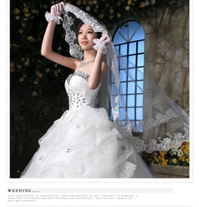 Detail of white bridal veil with floral lace embroidery and matching ruffled gloves