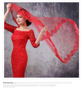 Close-up of red lace bridal veil and matching wedding gown with intricate floral patterns