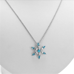 Elegant silver snowflake necklace with blue gemstone pendant on jewelry display stand