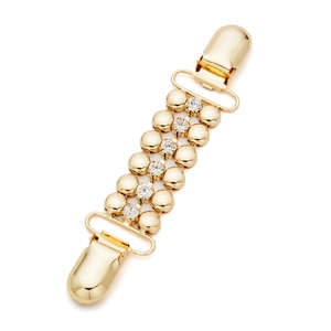 Dettaglio di una clip dorata vintage per cardigan con strass e doppie clip in metallo