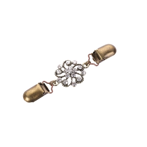 Dettaglio clip vintage in bronzo per cardigan con design floreale e strass chiari