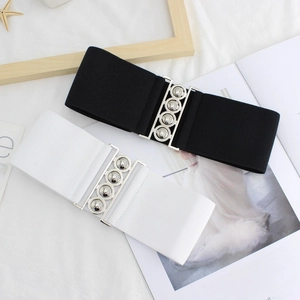 Set of black and white wide elastic waist belts with metallic ball buckles on a magazine