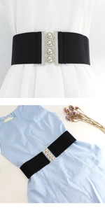 Detail of black elastic wide waist belt with silver metal buckle and embossed circles