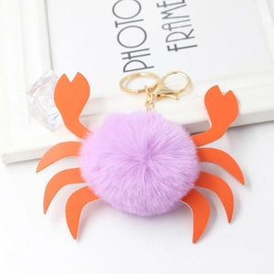 Portachiavi a granchio in peluche viola con pompon e chele in pelle arancione su bianco