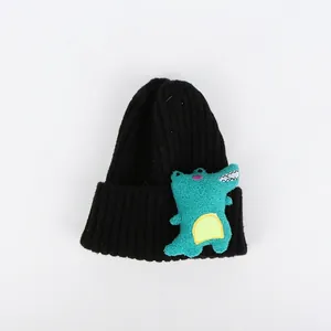Detail einer schwarzen Strickmütze mit einem 3D Cartoon Dino-Aufnäher für Kinder