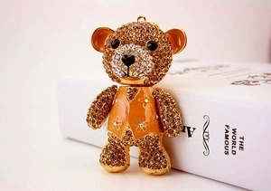 Detail of cute rhinestone teddy bear keychain with orange vest and golden finish