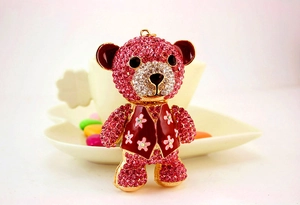 Close-up of pink rhinestone bear keychain with red enamel vest and gold alloy base