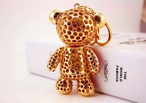 Detailed close-up of gold hollow bear keychain with red rhinestones and floral patterns