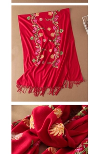 Detailed close-up of intricate floral embroidery and fringes on a red wool shawl