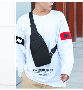 Detail of a black multi-functional chest bag with a headphone port on a male model outdoors